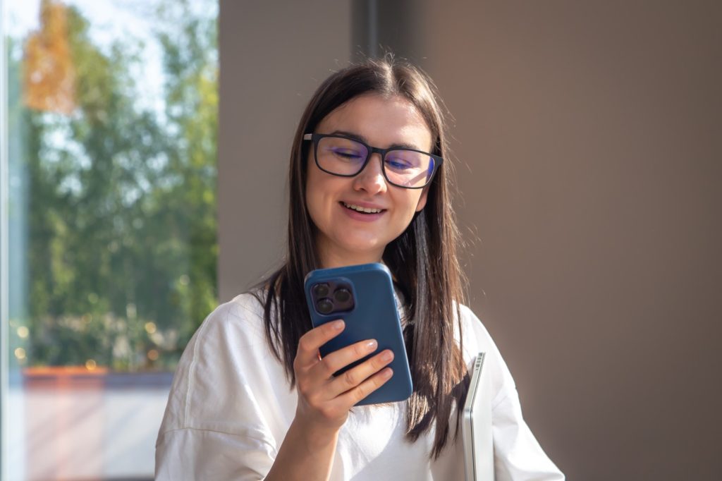 cheerful young woman glasses with smartphone her hands (1)