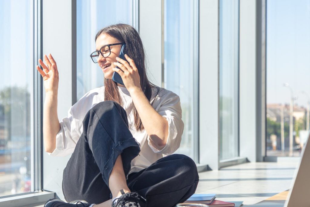 young woman glasses is talking smartphone near window (1)